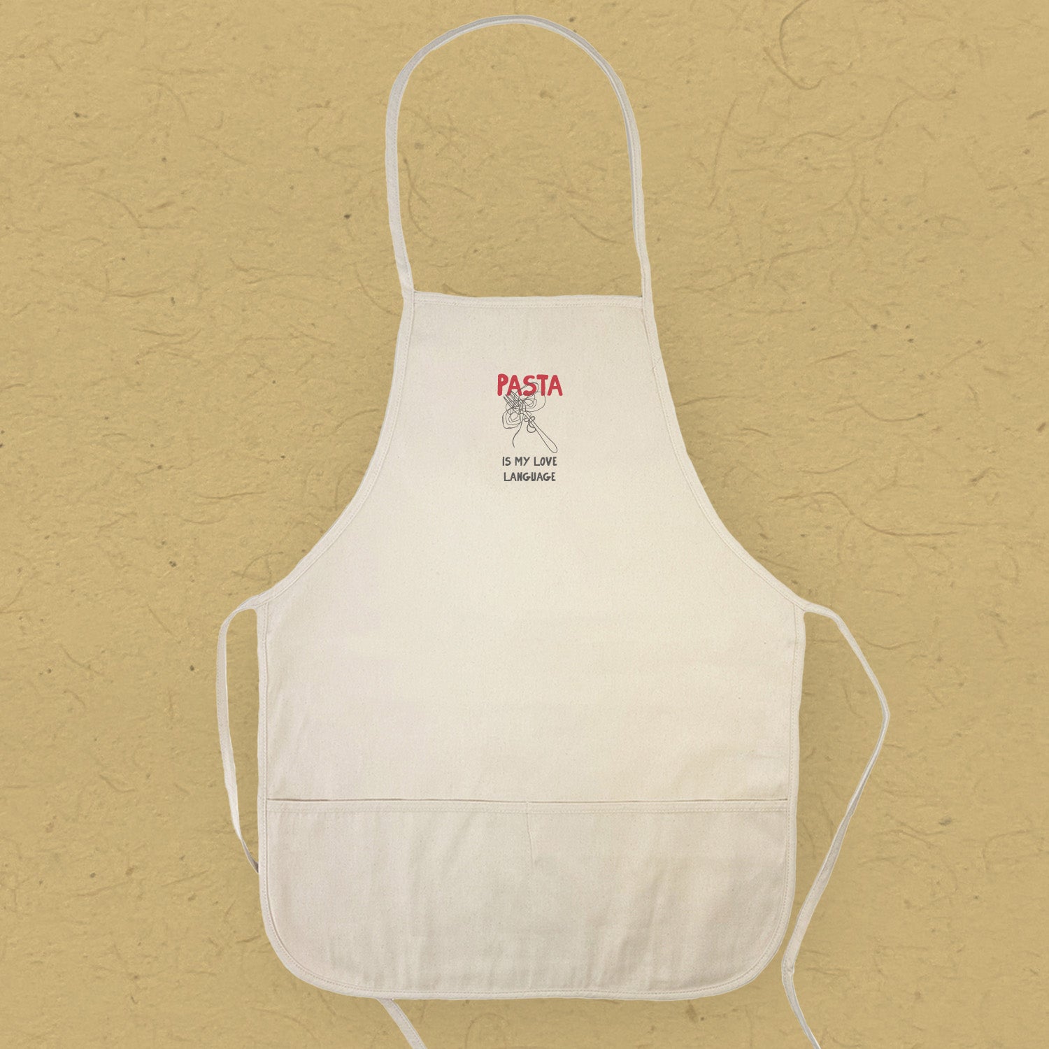A stylish women's apron with the phrase 'Pasta is My Love Language' printed on it, featuring a divided front pocket and natural twill ties.