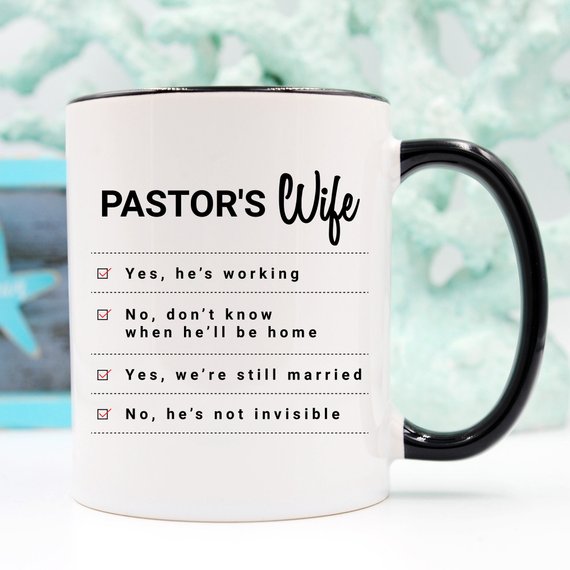 A humorous coffee mug featuring the phrase 'Yes, He Is Working; No, I Don't Know When He'll Be Home; No, He's Not Invisible' designed for pastor's wives.