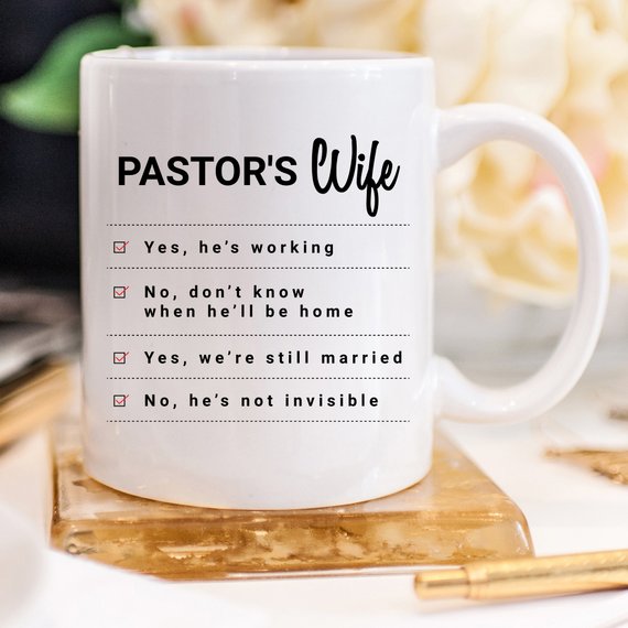 A humorous coffee mug featuring the phrase 'Yes, He Is Working; No, I Don't Know When He'll Be Home; No, He's Not Invisible' designed for pastor's wives.