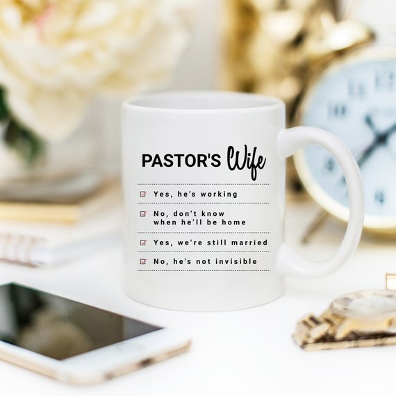A humorous coffee mug featuring the phrase 'Yes, He Is Working; No, I Don't Know When He'll Be Home; No, He's Not Invisible' designed for pastor's wives.