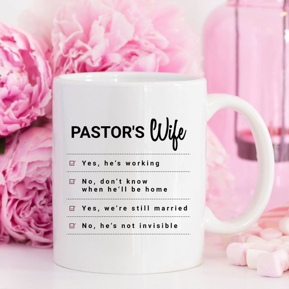 A humorous coffee mug featuring the phrase 'Yes, He Is Working; No, I Don't Know When He'll Be Home; No, He's Not Invisible' designed for pastor's wives.