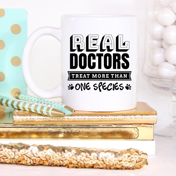 A humorous coffee mug featuring the phrase 'Real Doctors Treat More Than One Species', crafted from high-quality ceramic, perfect for animal lovers.