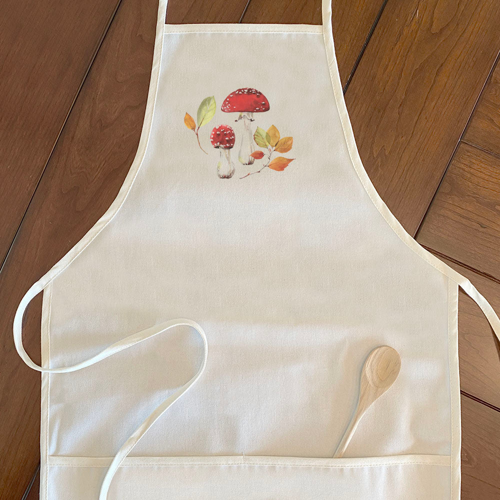 A stylish women's apron featuring a red capped mushroom design, made from durable cotton canvas with adjustable neck and twill ties.