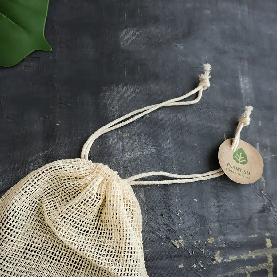 Reusable cotton rounds made from bamboo charcoal, displayed in an organic mesh bag, showcasing their eco-friendly design.