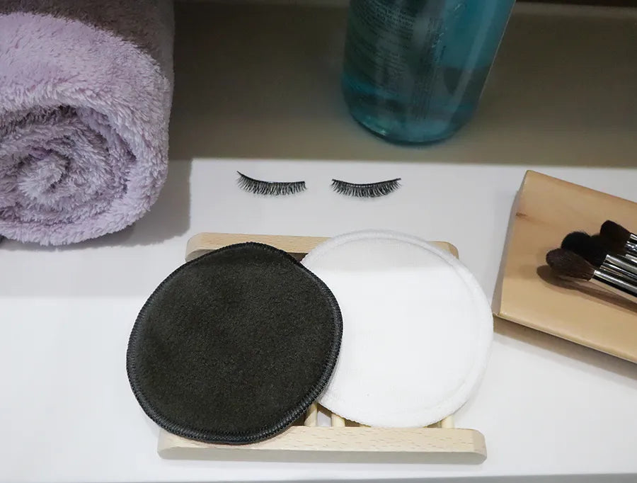 Reusable cotton rounds made from bamboo charcoal, displayed in an organic mesh bag, showcasing their eco-friendly design.