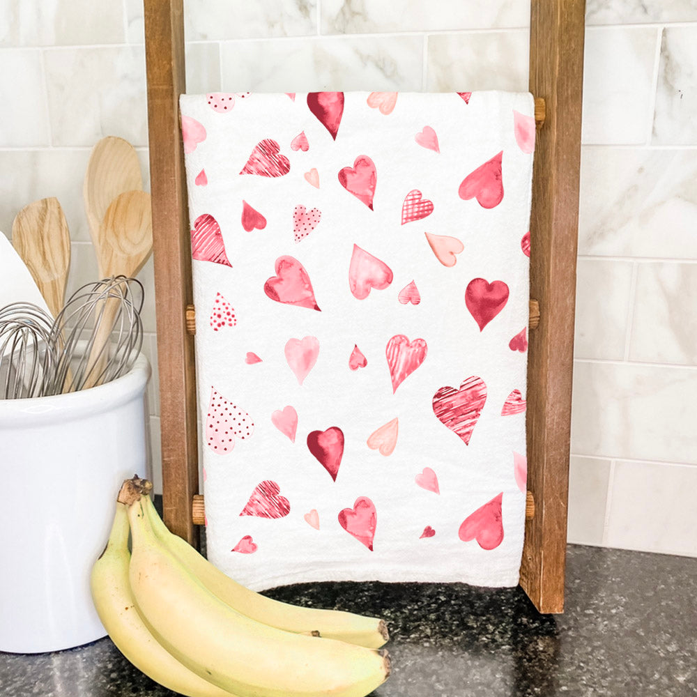 A vibrant cotton tea towel featuring a scattered hearts pattern, perfect for kitchen use.