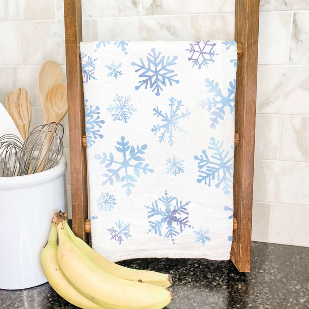 A beautifully designed cotton tea towel featuring a snowflakes pattern, showcasing vibrant colors and hemmed edges, perfect for kitchen use.
