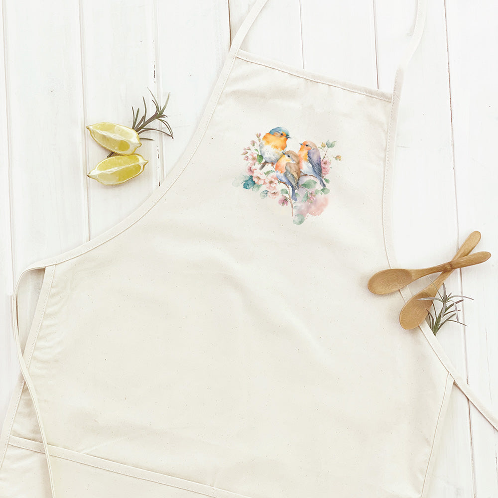 A stylish women's apron featuring a watercolor design of spring birds on a cotton canvas fabric, with natural twill ties and a divided front pocket.