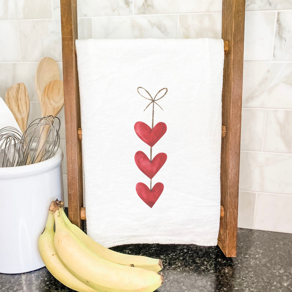 A vibrant cotton tea towel featuring a String of Hearts design, perfect for kitchen use.