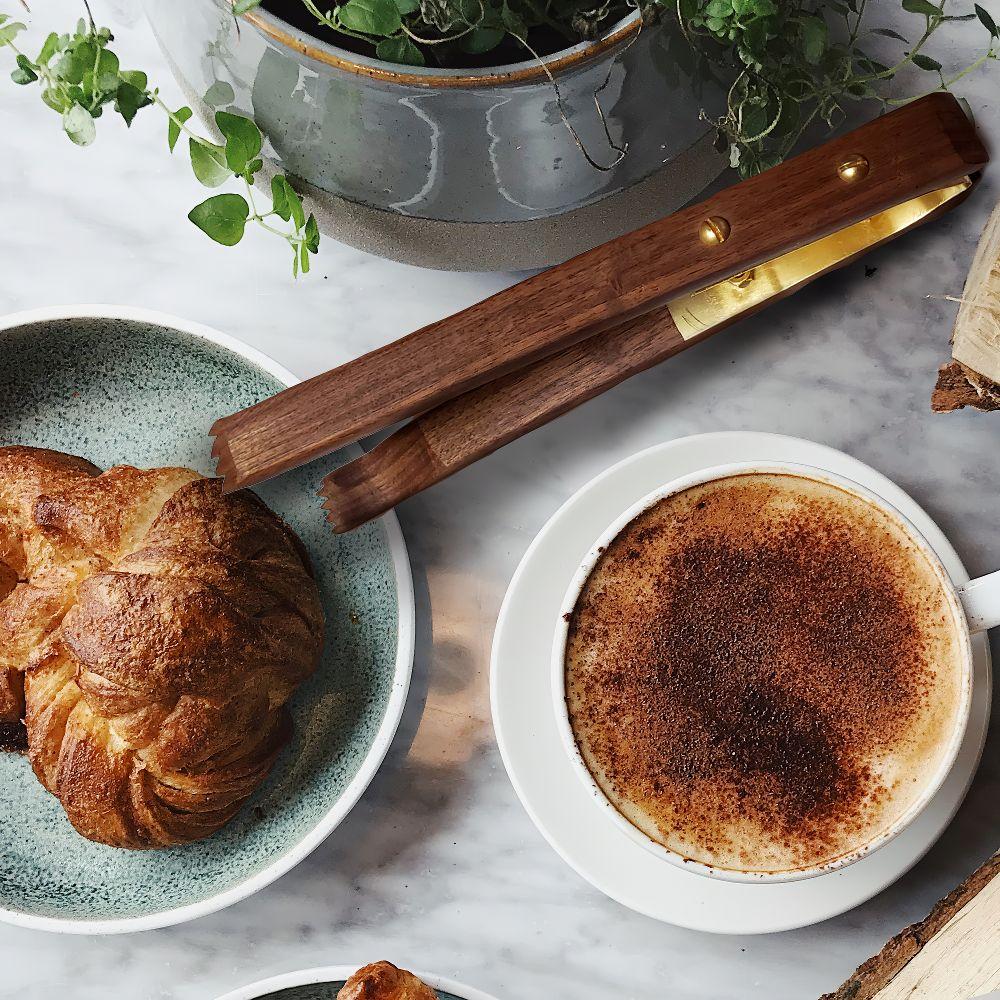 10-inch walnut and brass tongs designed for kitchen use, featuring grip ends with teeth for better food handling.