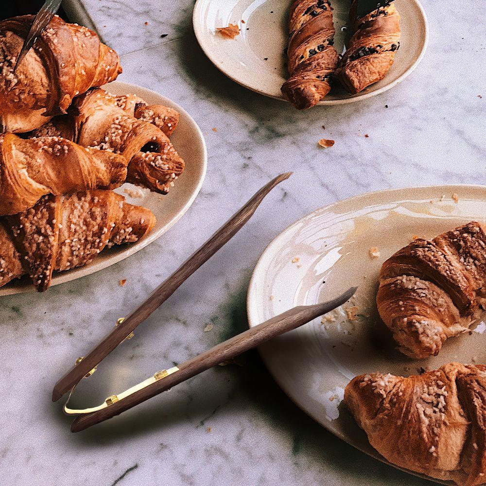 10-inch walnut and brass tongs designed for kitchen use, featuring grip ends with teeth for better food handling.