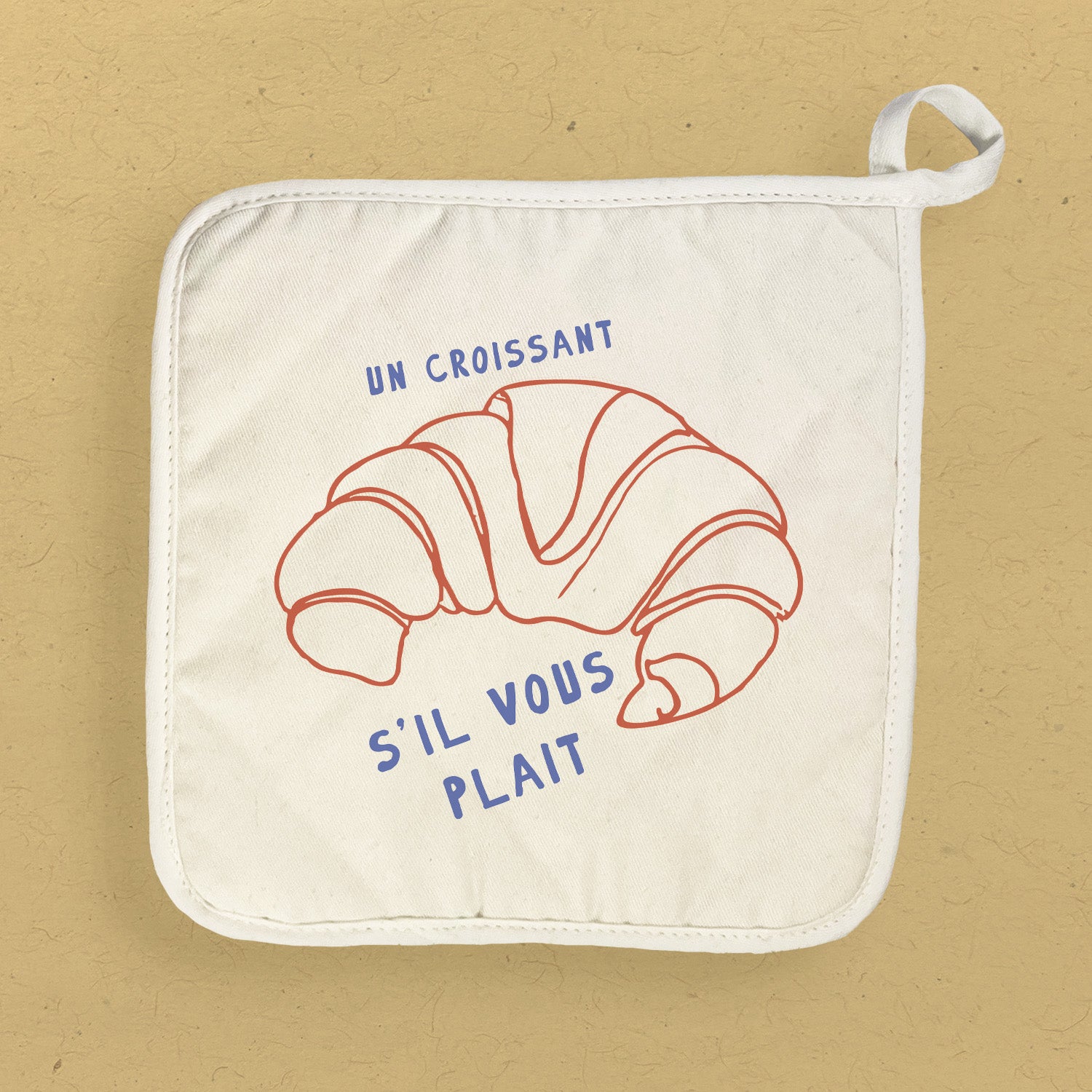 Un Croissant Cotton Pot Holder featuring a vibrant design, made from natural cotton and terry cloth, perfect for protecting surfaces from hot cookware.