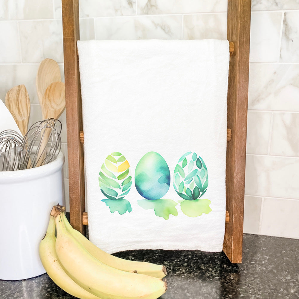 A vibrant cotton tea towel featuring a watercolor design of colorful Easter eggs, perfect for festive kitchen decor.