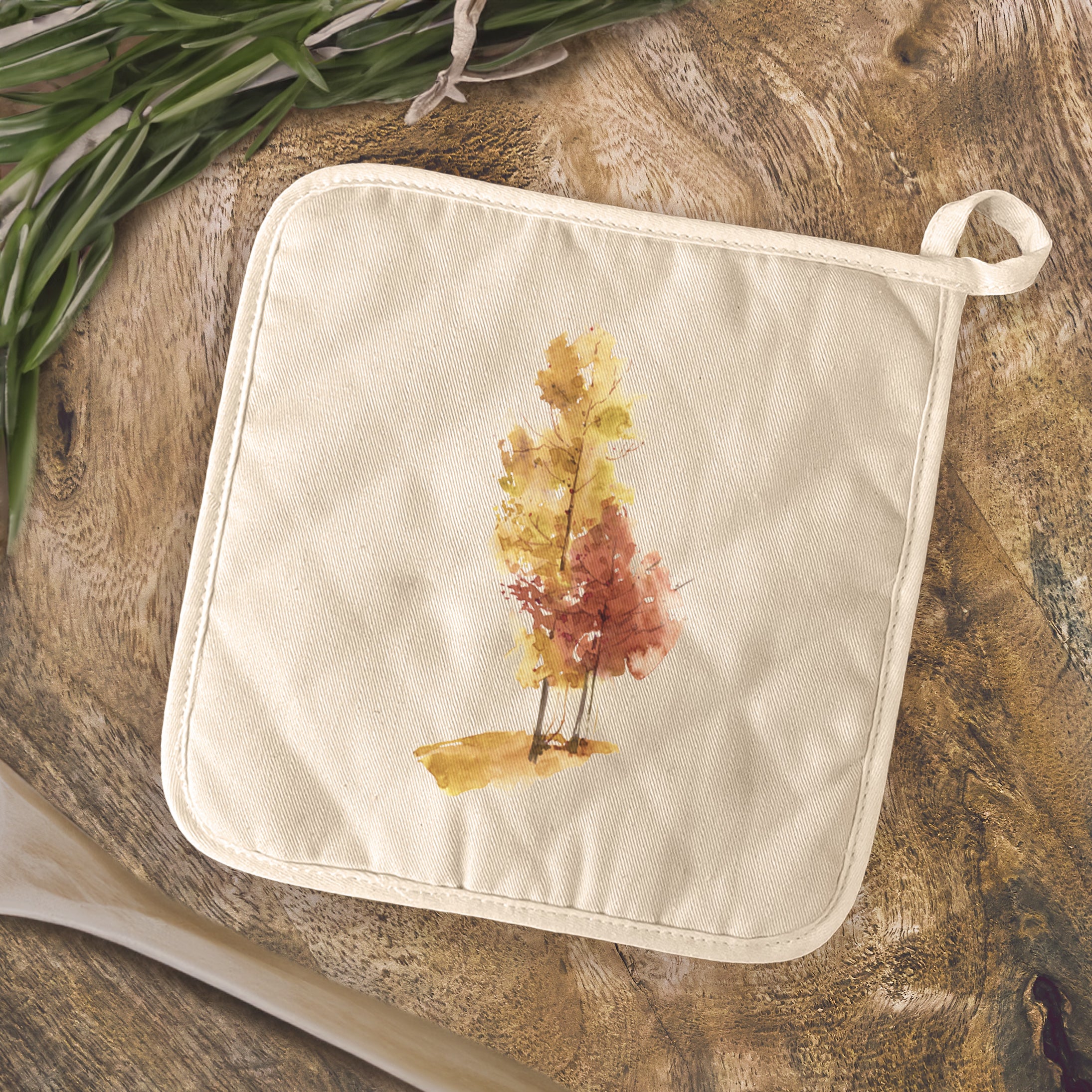 A square cotton pot holder featuring a vibrant watercolor design of fall trees, perfect for protecting surfaces from hot cookware.