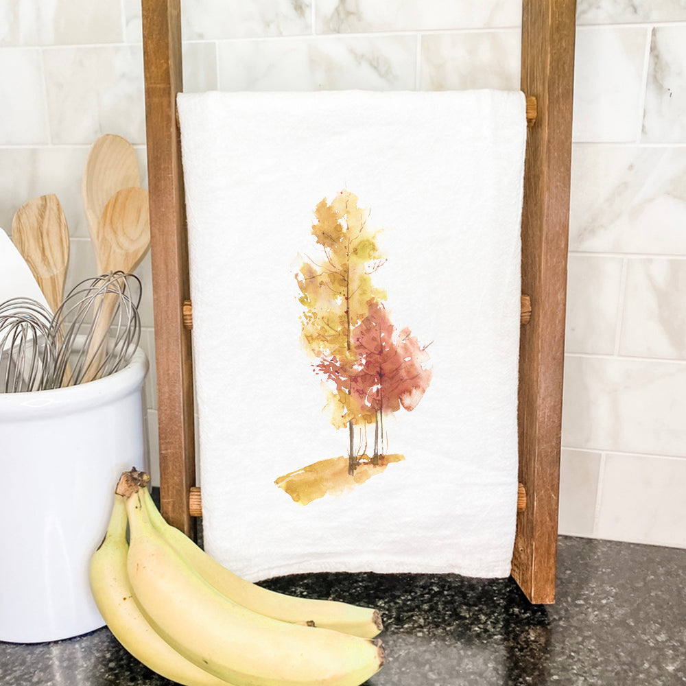 A vibrant cotton tea towel featuring watercolor fall trees design, perfect for kitchen use and seasonal decor.