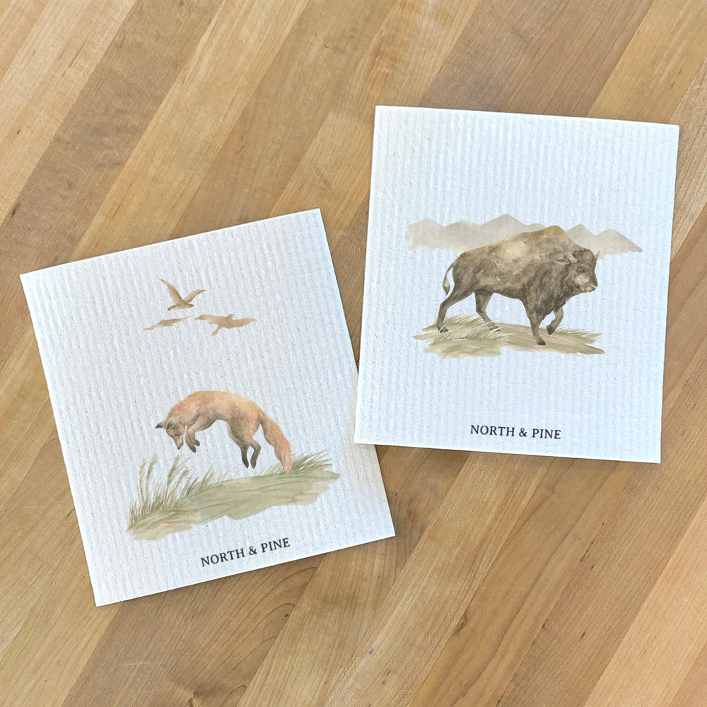Two Swedish dish cloths featuring watercolor designs of a fox and a bison, eco-friendly and reusable.