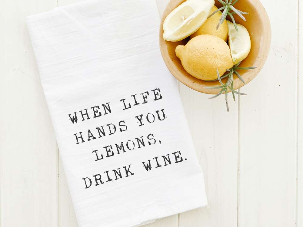 Cotton tea towel featuring the phrase 'When Life Hands You Lemons, Drink Wine' with a vibrant design, perfect for kitchen use.