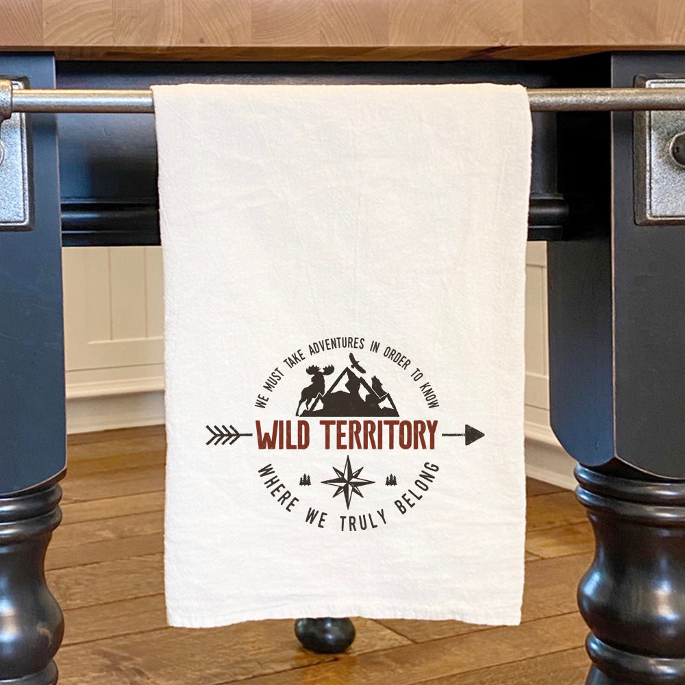 Wild Territory Badge Cotton Tea Towel featuring vibrant design and hemmed edges, perfect for kitchen use.