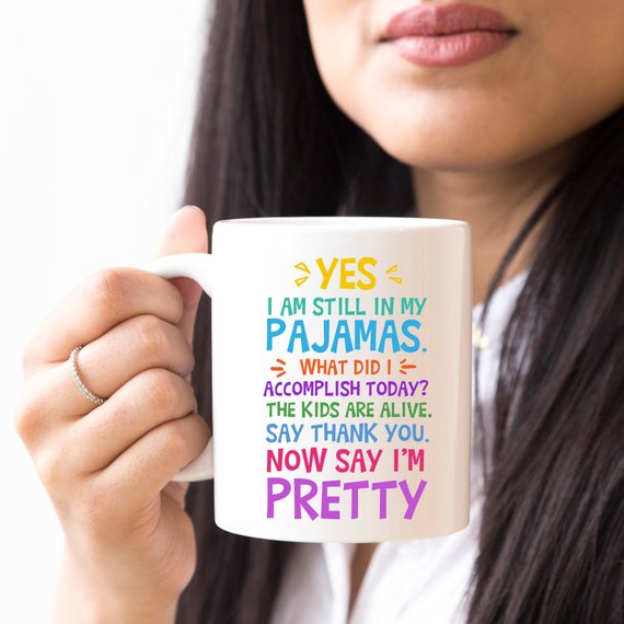 A humorous coffee mug with the phrase 'Yes, I Am Still In My Pajamas, Now Say I’m Pretty' printed on it, showcasing a fun design.