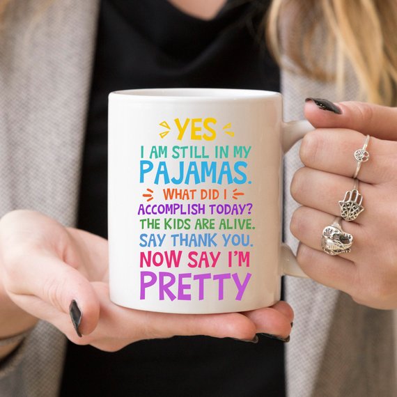 A humorous coffee mug with the phrase 'Yes, I Am Still In My Pajamas, Now Say I’m Pretty' printed on it, showcasing a fun design.
