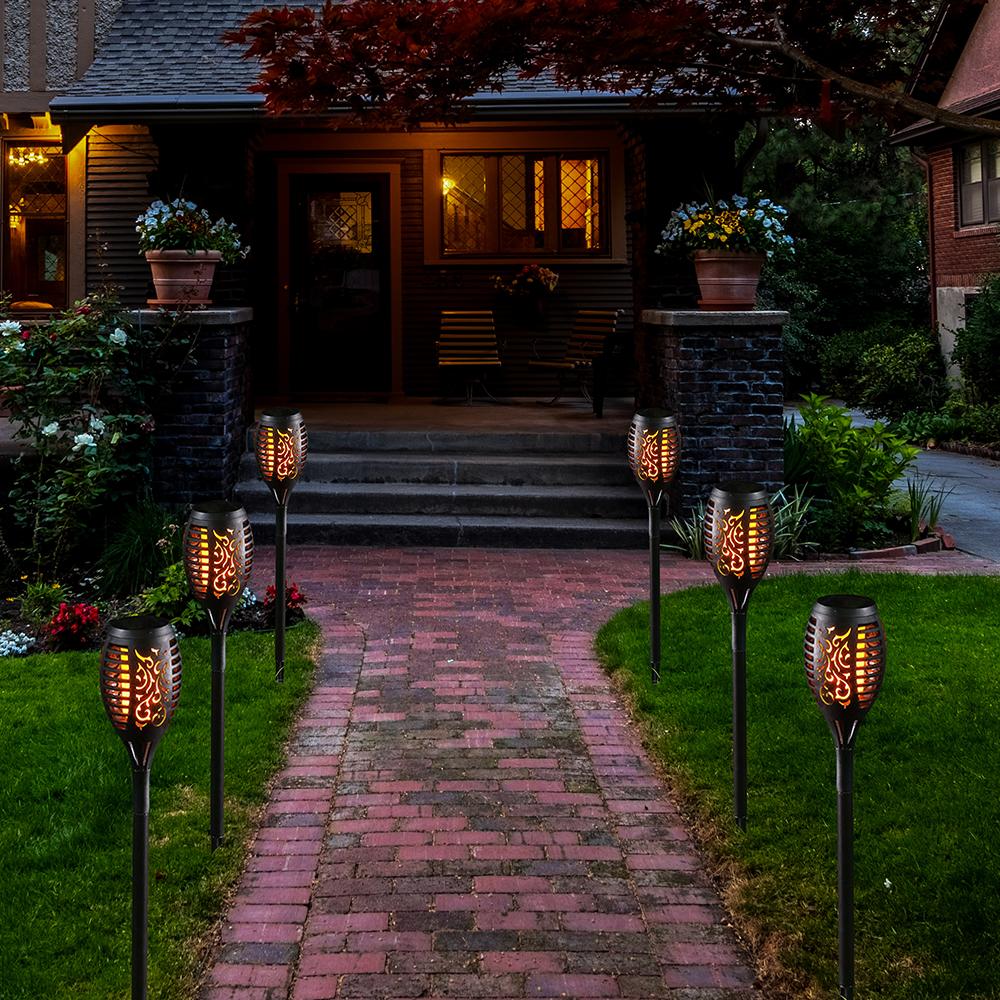 Four solar lights with flickering flame effect, designed for outdoor use, showcasing a romantic ambiance in a garden setting.