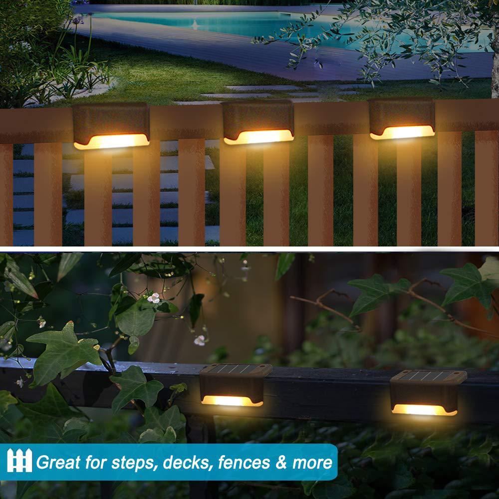 Four solar deck lights installed on a wooden patio, illuminating the pathway with a warm glow, showcasing their waterproof design.