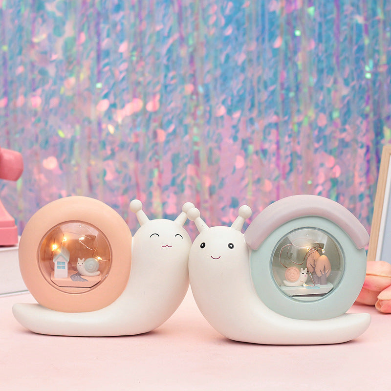 A cute cartoon snail-shaped night lamp and piggy bank in medium blue and yellow colors, perfect for children's rooms.