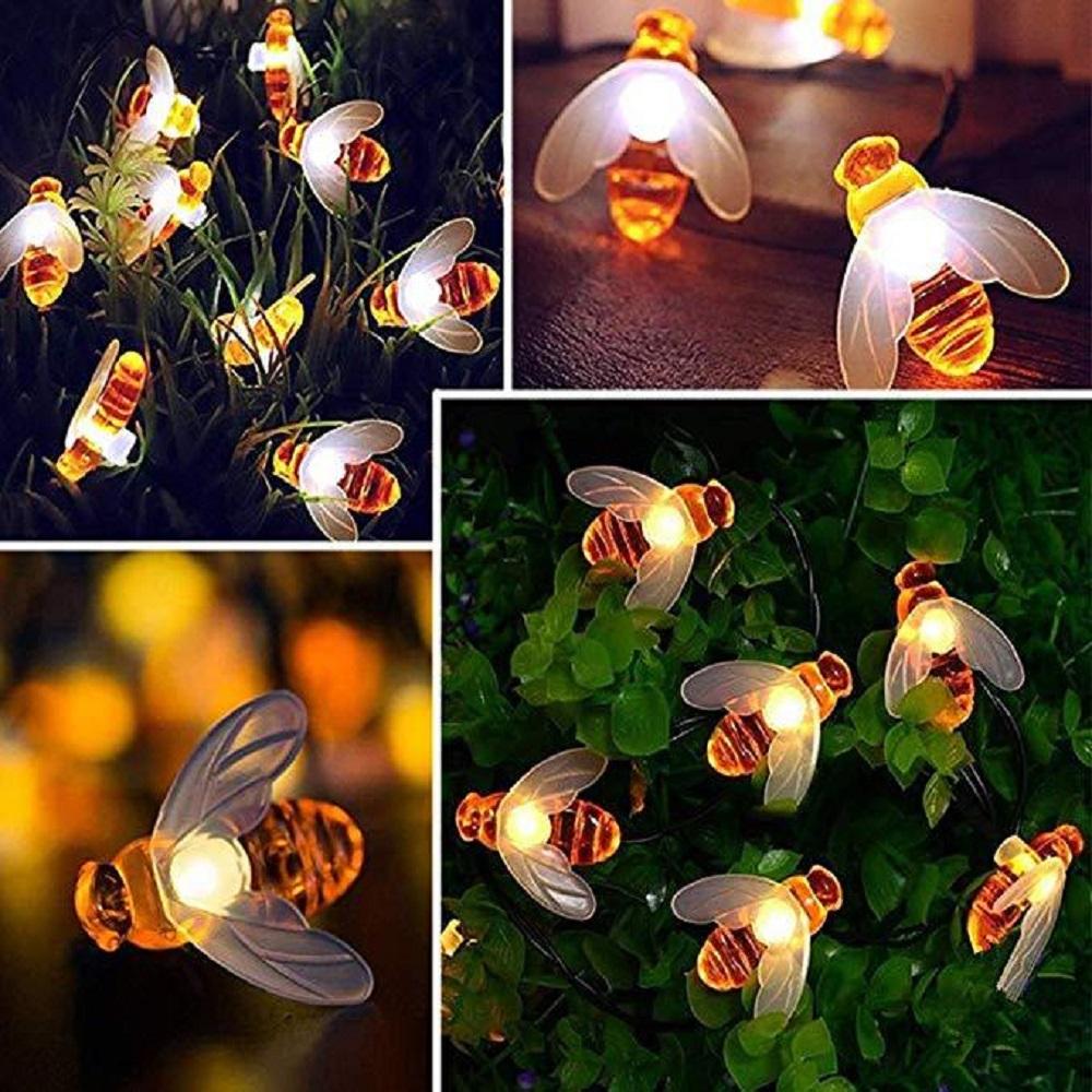 A string of solar-powered LED fairy lights shaped like cute honey bees, illuminating a garden at night.