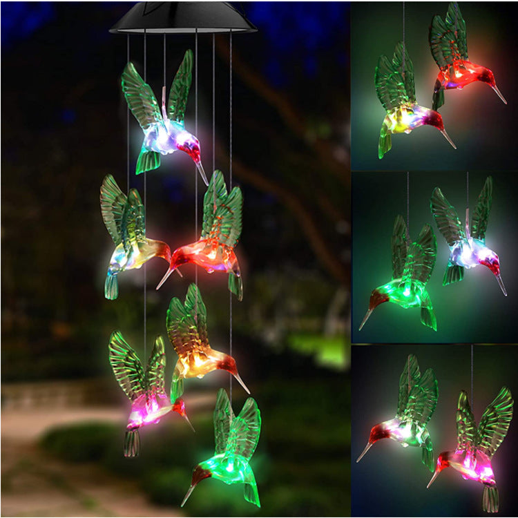 Outdoor Solar Wind Chime Lamp with hummingbird and butterfly designs, glowing softly at night.