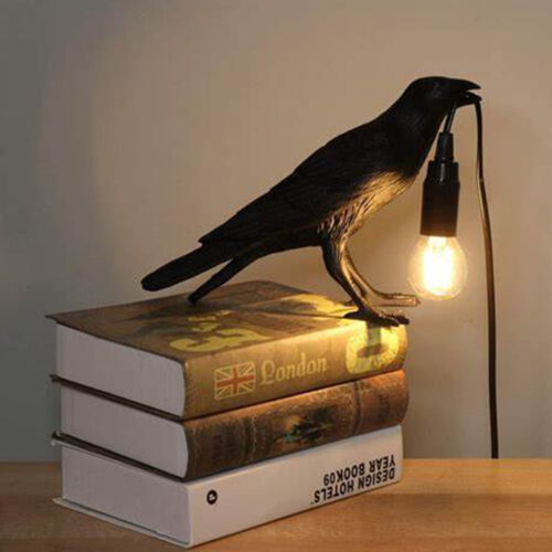 A stylish raven desk lamp with a crow design, featuring an open beak holding the lamp cord, perfect for Halloween decor.