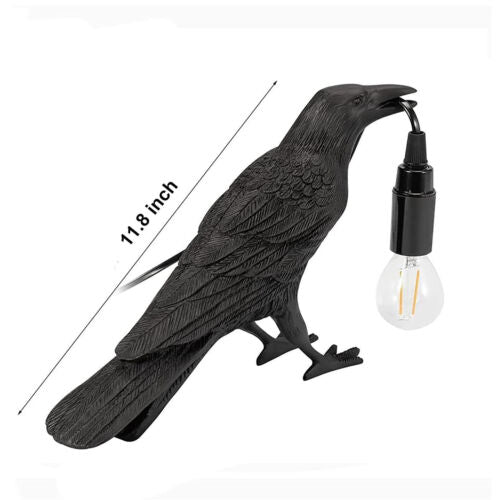 A stylish raven desk lamp with a crow design, featuring an open beak holding the lamp cord, perfect for Halloween decor.