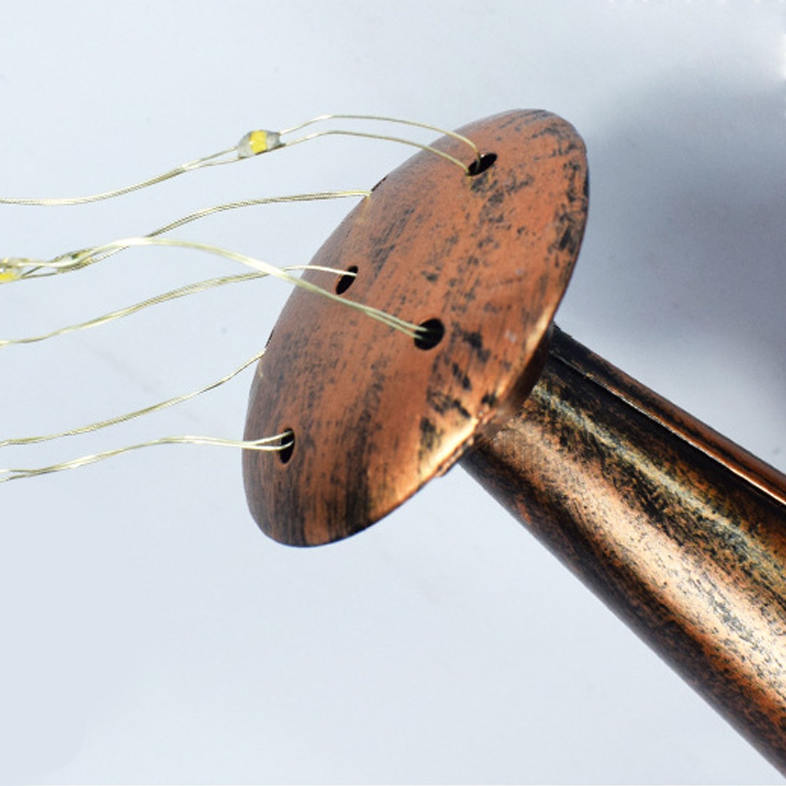 A decorative solar watering can light with LED string lights, hanging on a shepherd hook, illuminating a garden with beautiful patterns.