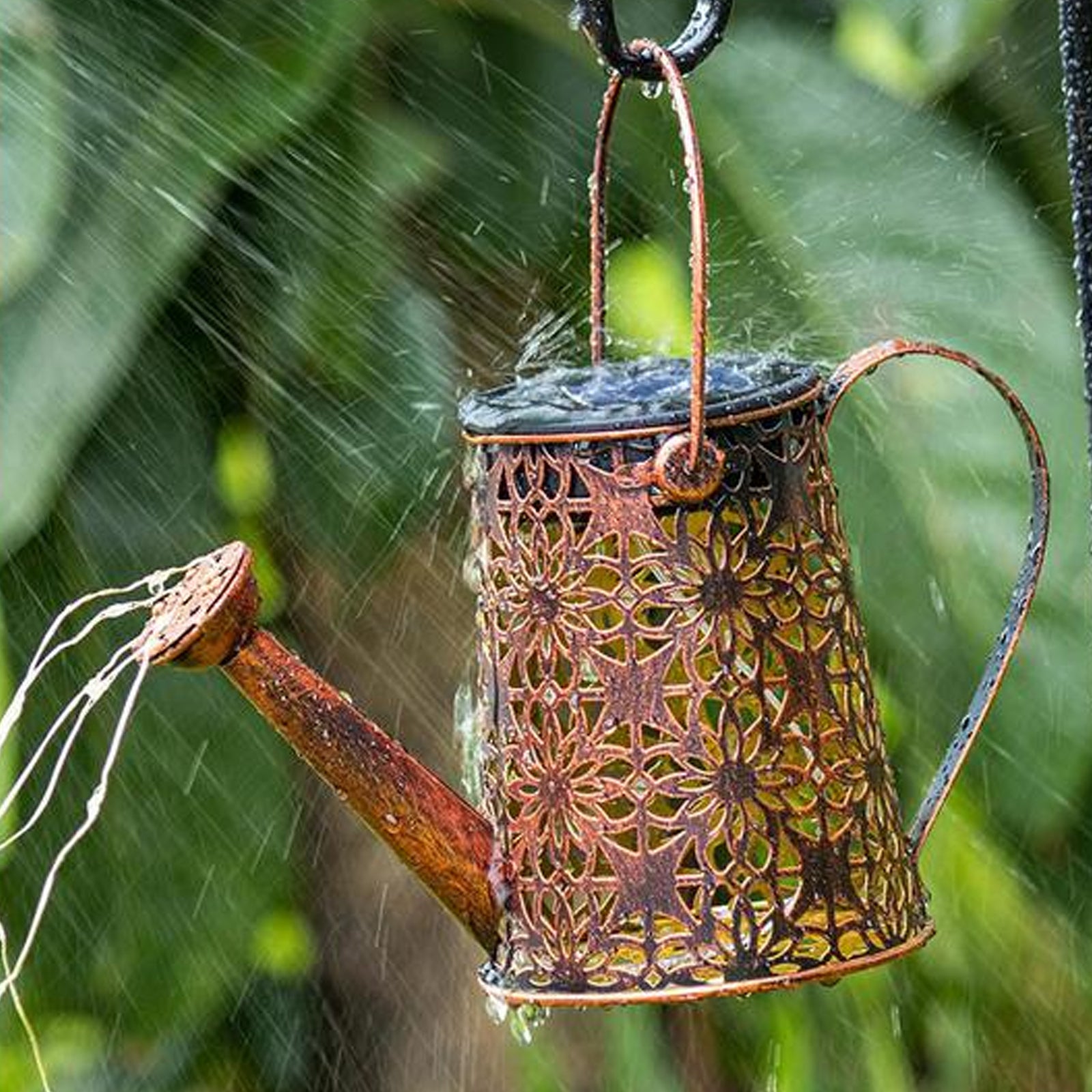 A decorative solar watering can light with LED string lights, hanging on a shepherd hook, illuminating a garden with beautiful patterns.