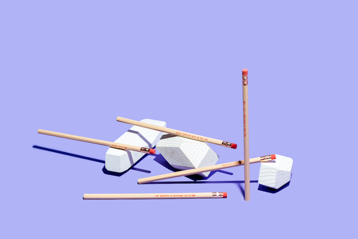 EXISTENTIAL CRISIS Pencil Set featuring five cedar pencils in cream color with blood-red stamped phrases and gold ferrules.