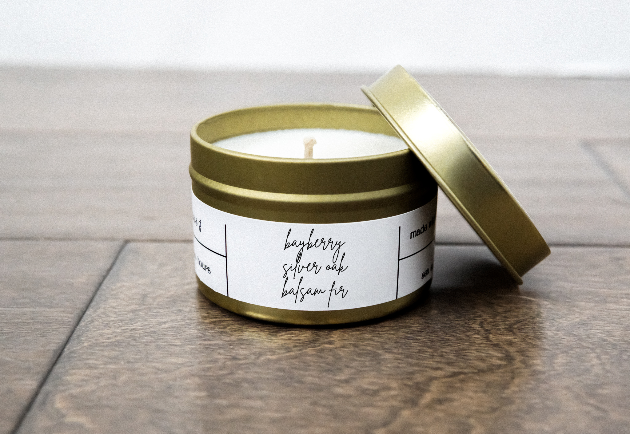 A gold travel candle in a tin jar, featuring a blend of bayberry, silver oak, and balsam fir scents, with a cozy ambiance.