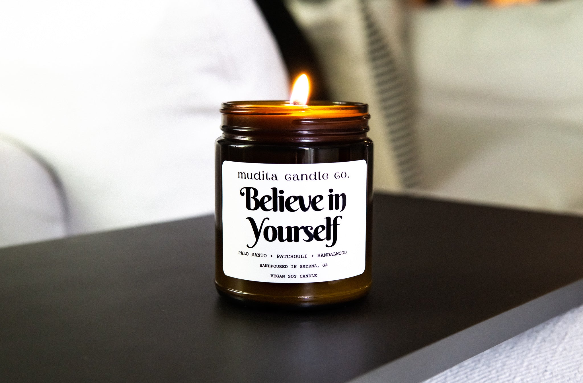 Believe in Yourself candle featuring palo santo, patchouli, and sandalwood scents in a reusable amber glass jar.