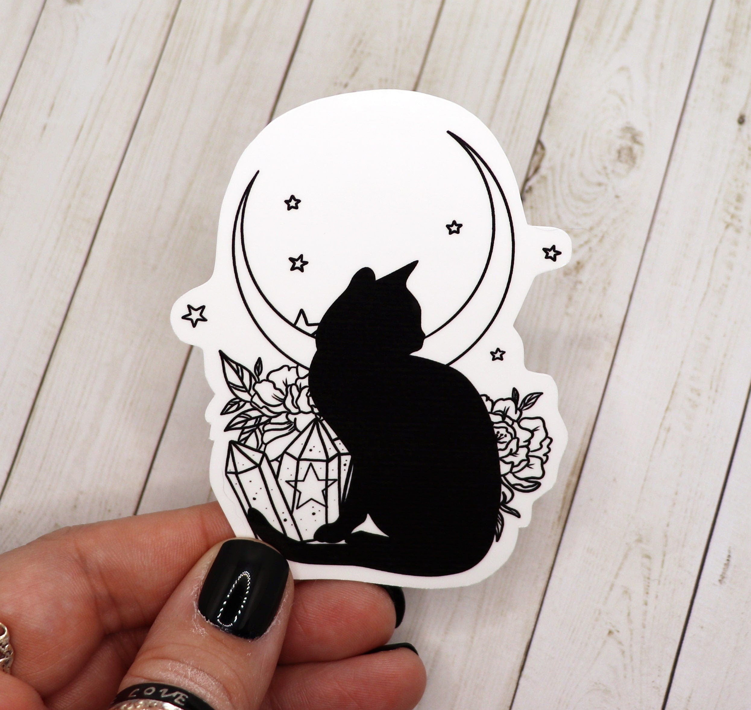 A vinyl sticker featuring a black and white cat sitting on a crescent moon, designed for decoration.
