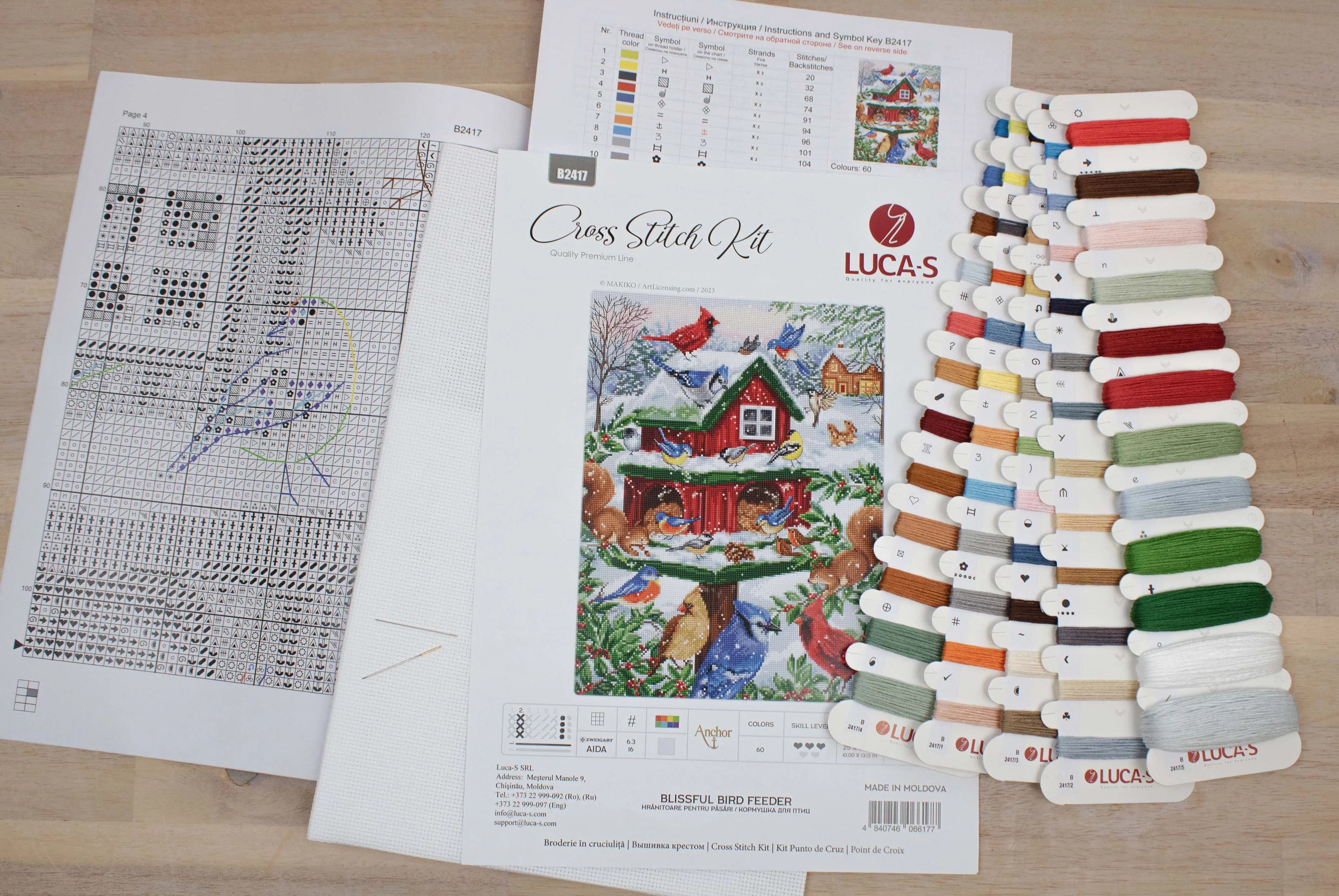 Blissful Bird Feeder B2417L Counted Cross-Stitch Kit featuring colorful threads, Aida canvas, and a needle.