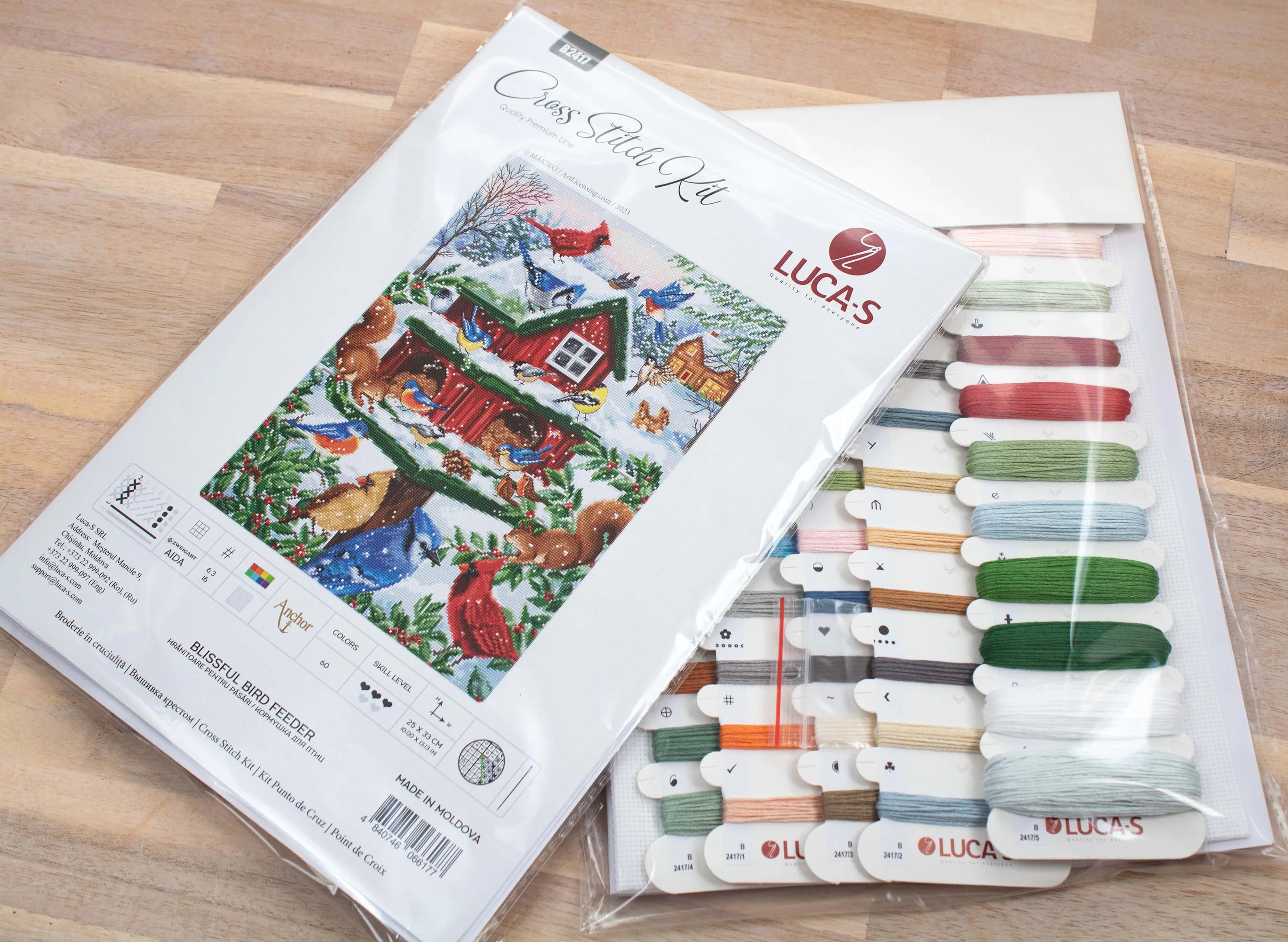 Blissful Bird Feeder B2417L Counted Cross-Stitch Kit featuring colorful threads, Aida canvas, and a needle.