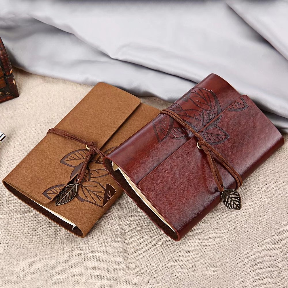Two leather-bound journals with leaf designs.