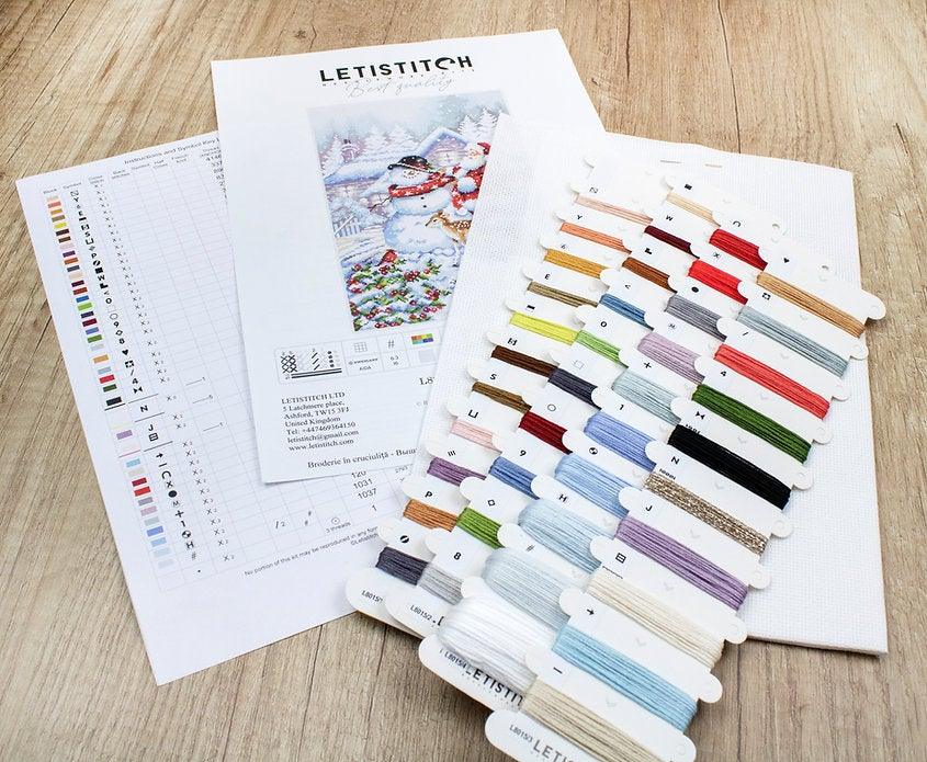 Counted Cross Stitch Kit featuring a Snowman and Santa design, including colorful threads and a needle on a canvas.