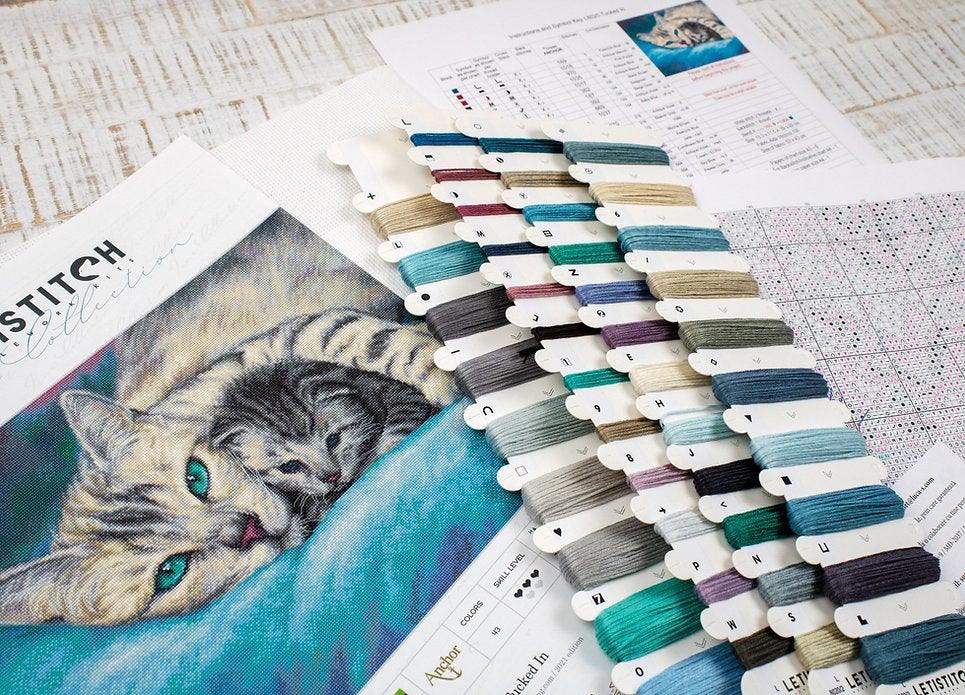 Counted Cross Stitch Kit Tucked In L8020 featuring vibrant threads, Aida canvas, and included needle and instructions.