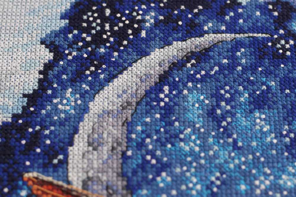 Cross-stitch kit Above the Clouds AH-093 featuring dark blue canvas, colorful floss, and stitching supplies.