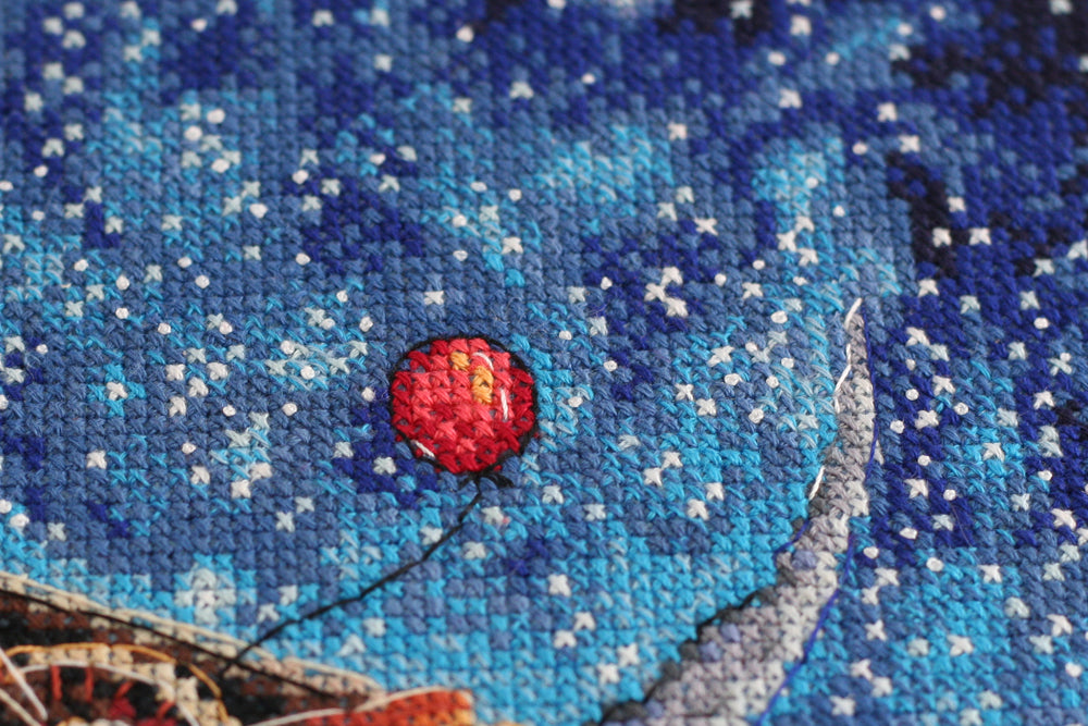 Cross-stitch kit Above the Clouds AH-093 featuring dark blue canvas, colorful floss, and stitching supplies.