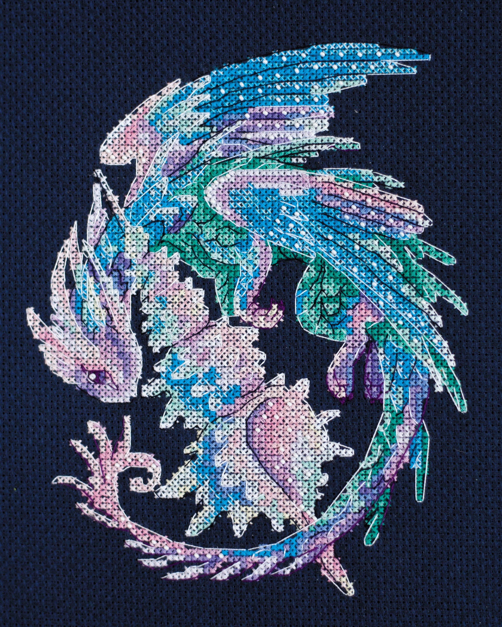 Cross-stitch kit featuring a Baby Dragon design with dark blue canvas, colorful floss, and beads.