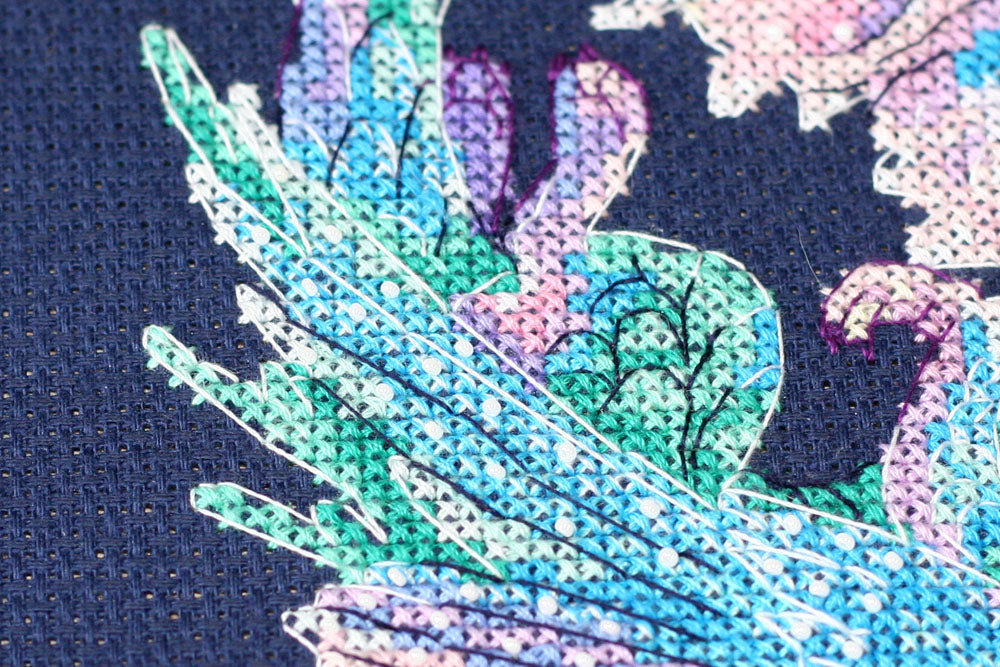 Cross-stitch kit featuring a Baby Dragon design with dark blue canvas, colorful floss, and beads.