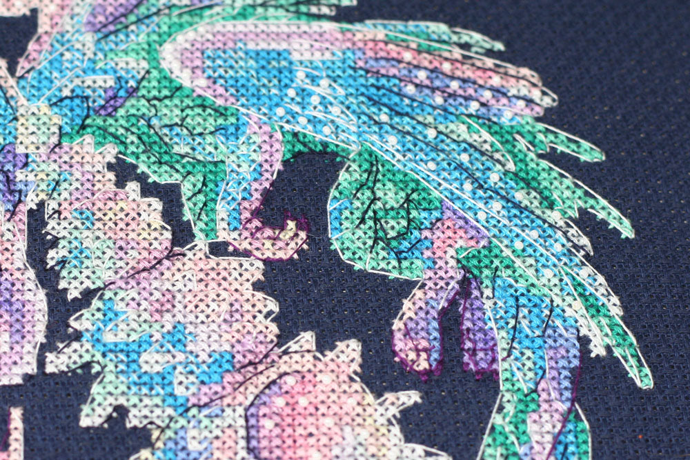 Cross-stitch kit featuring a Baby Dragon design with dark blue canvas, colorful floss, and beads.