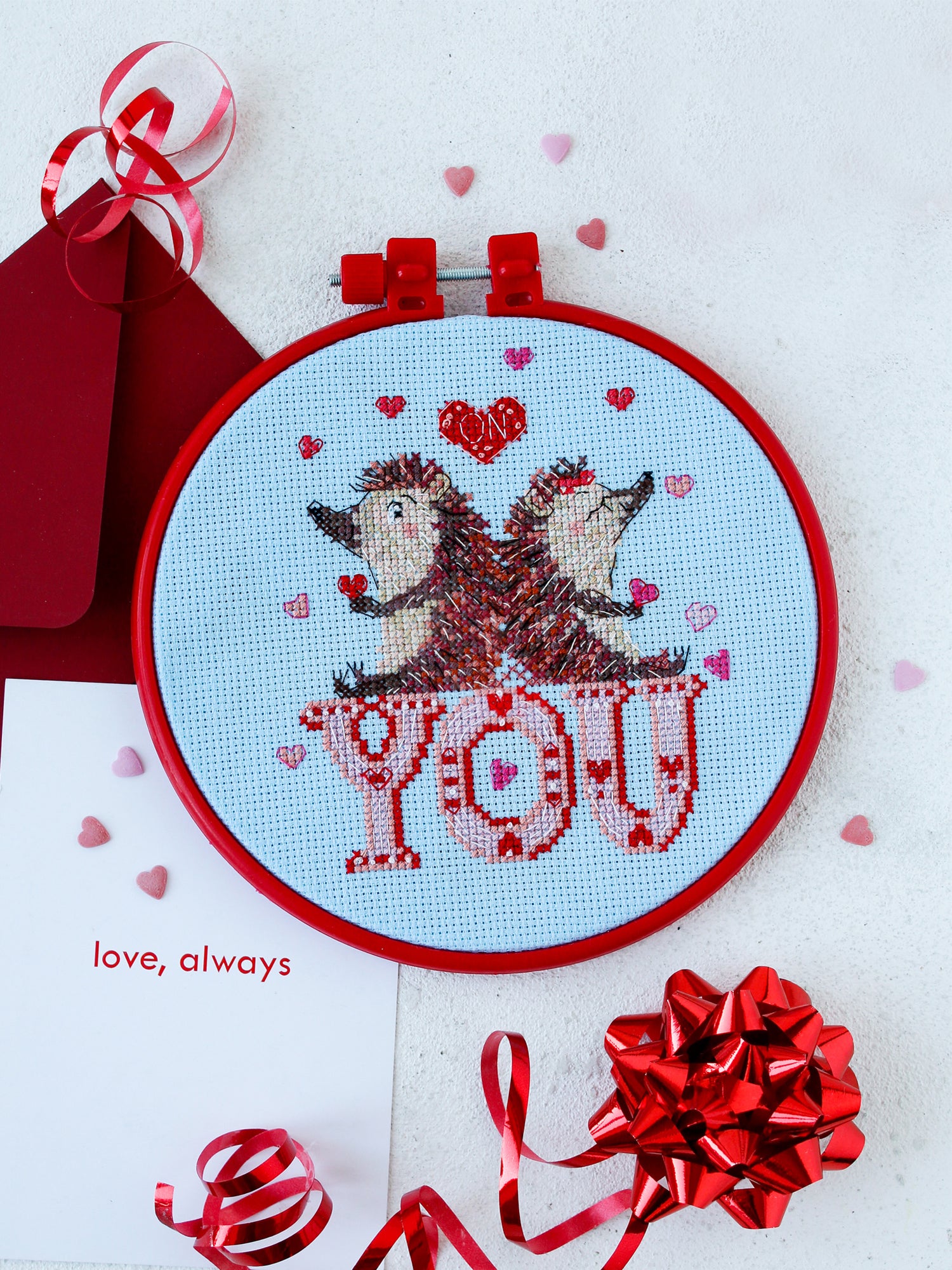 Cross-stitch kit featuring adorable hedgehogs with blue canvas and colorful floss.