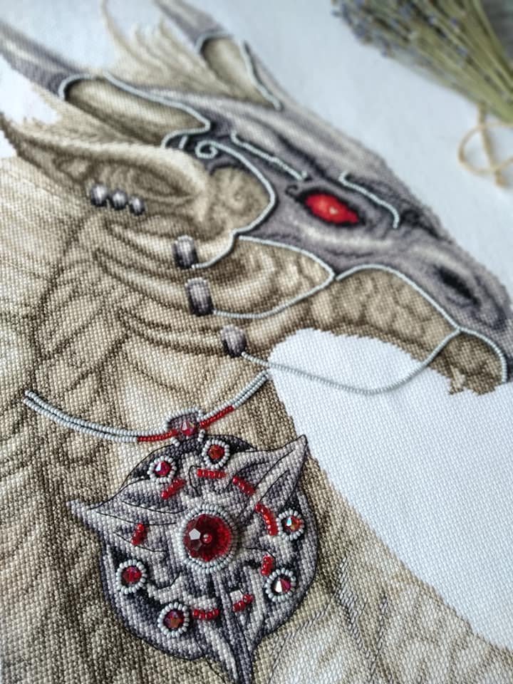 Cross-stitch kit M-319C 'Guardian of treasure' featuring colorful threads, beads, and Aida fabric.