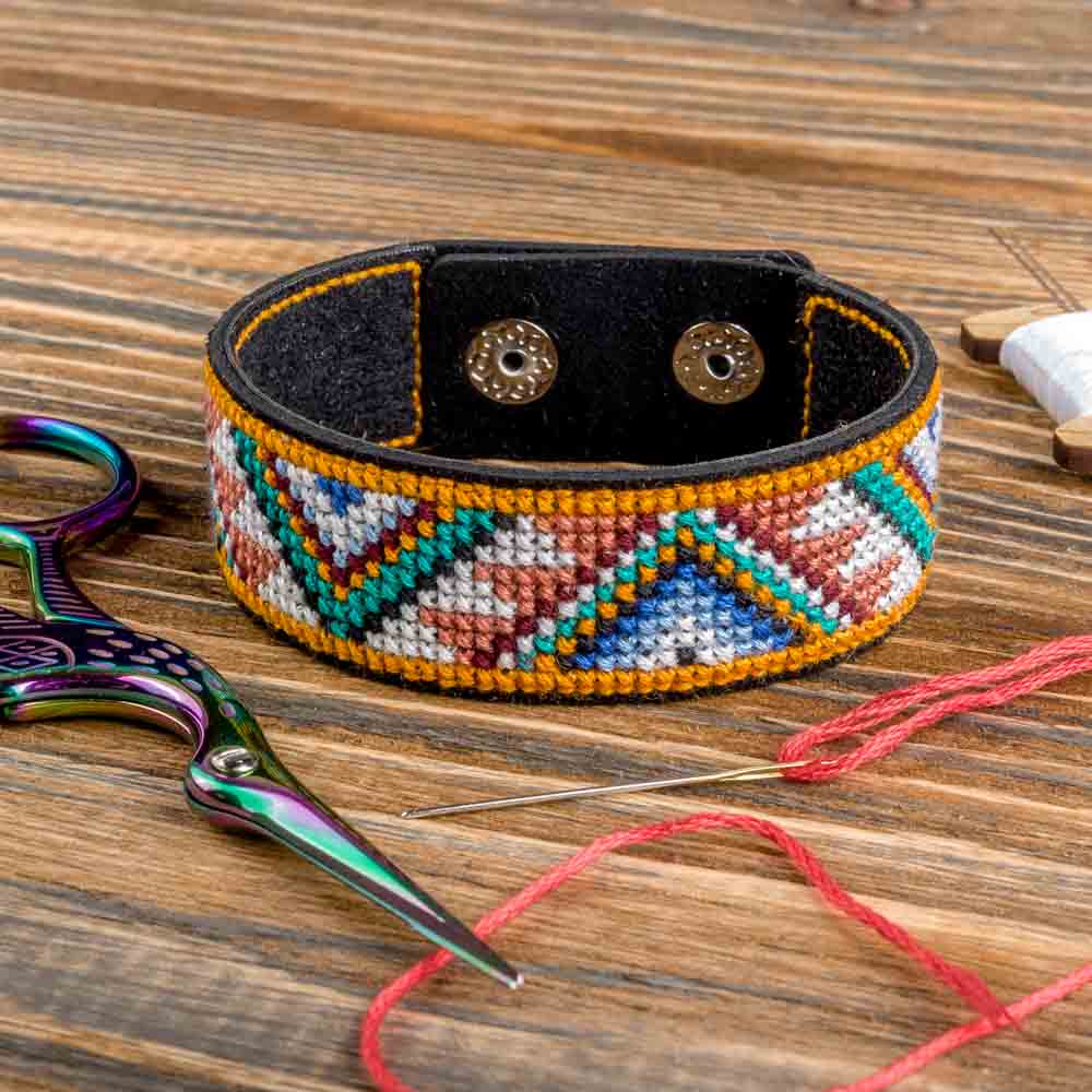 Cross-stitch kit on artificial leather FLHL-031 featuring colorful embroidery floss and leather blanks for bracelet making.